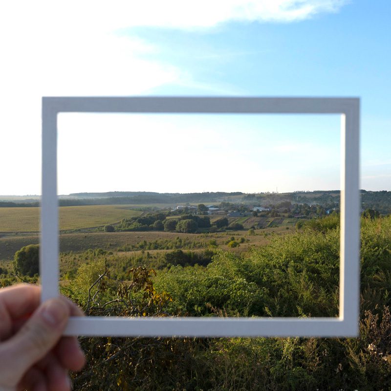 Hand hält Bilderrahmen in Natur